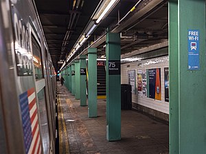 View of the platform, with green support columns and a wall with green and white tiles