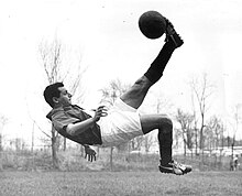 Photographie en noir et blanc d'un homme avec les pied en l’air, percutant un ballon de foot