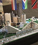 Une maquette en petits blocs du village olympique. En avant-plan, des petits blocs indiquent le nom de Montréal ; en fond, on voit plusieurs drapeaux.