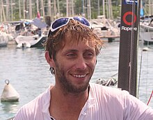 Portrait, souriant à bord d'un voilier, cheveux en désordre collés par l'eau de mer.