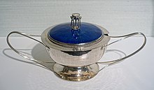 Shiny silver bowl with two elongated handles and a bright blue lid.