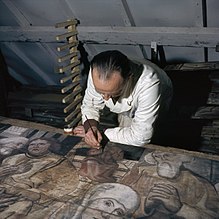 Photographie d’un homme tendant un pinceau sur une toile.