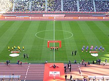 Looking at the centre of the pitch from the stands, both teams are in formation for pre-game photos