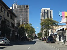 A street scene in downtown Windsor. At left is a tall, 34-story condominium building with various communications antennas on top