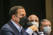 Three men in business suits, wearing masks