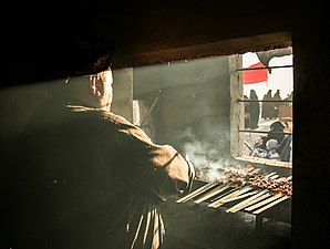 En man som grillar kött för pilgrimer.