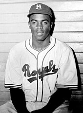 A black man in a baseball uniform with the words "Royals" and a baseball cap with the letter "M".