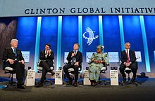 Macri seated onstage with Bill Clinton, two other men and a woman