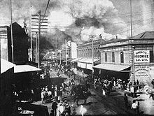 people in street watching fire in distance