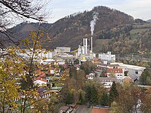 Panorama über ein Werksgelände, das von Bergen umgeben ist.