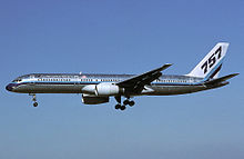 Side view of silver twinjet in flight, with "757" markings on tail.