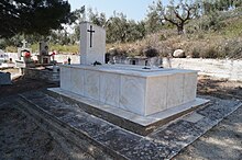 A marble tomb in a churchyard, with a prominent Christian cross decoration