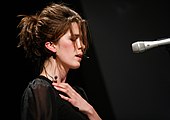 Imogen Heap singing onto a mic with her eyes closed