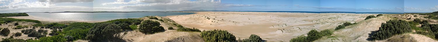 Panorama of Shallow Inlet showing expanses of water and sand with distant hills in the background