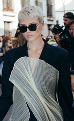 European origin woman with dark glasses and silver-blonde short hair wearing a designer jacket