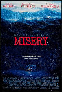 A lit-up cabin is surrounded in the dark by trees and a mountain, with the word "MISERY" faintly superimposed around the area.