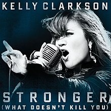 A blue-tint-in-a-black-and-white image of a woman singing. Her right hand is holding a vintage carbon microphone in front of her mouth. The microphone's wire is resting on her left hand between her thumb and her index finger. Below her, the words "Stronger" and "(What Doesn't Kill You)" are written in white upper-case letters.