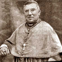 Newspaper clipping: black and white photograph of mature white man with spectacles and moustache, dressed in a bishop's gown.