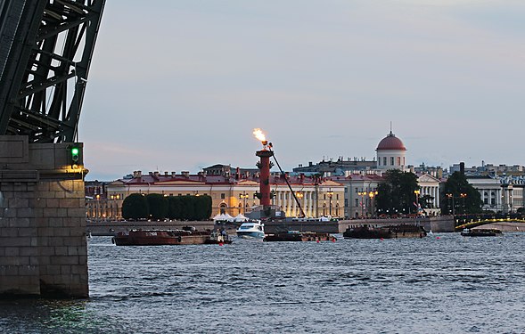 Weiße Nacht über der Newa. Feiertag "Scharlachrotes Segel 2019" in St. Petersburg. Offene Spanne der Trinity Bridge. Rostralsäulen mit brennendem Feuer - architektonische Strukturen auf der Nehrung der Wassiljewski-Insel. Im 19. Jahrhundert diente sie als Leuchtturmhafen der nördlichen Hauptstadt.