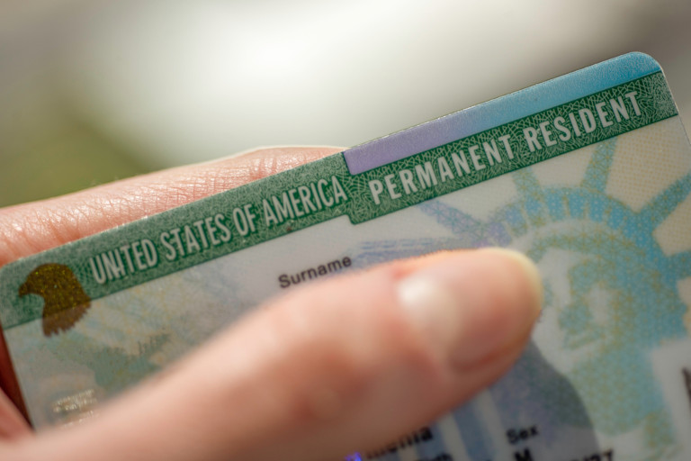 Woman's hand shown holding a US green card.