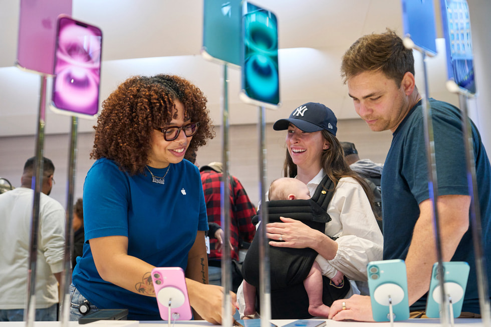 A team member assists customers exploring the new iPhone 16 lineup at Apple Fifth Avenue in New York City.