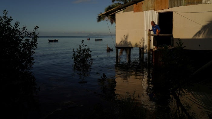 Local resident of Veivatuloa Village in Fiji looks out at seawater flooding around his home at high tide in July 16, 2022.