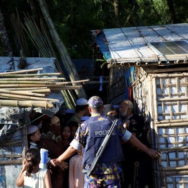 Police officers stand guard in front of Rohingya refugees at Kutupalong camp in Cox’s Bazar, Bangladesh, September 30, 2021.