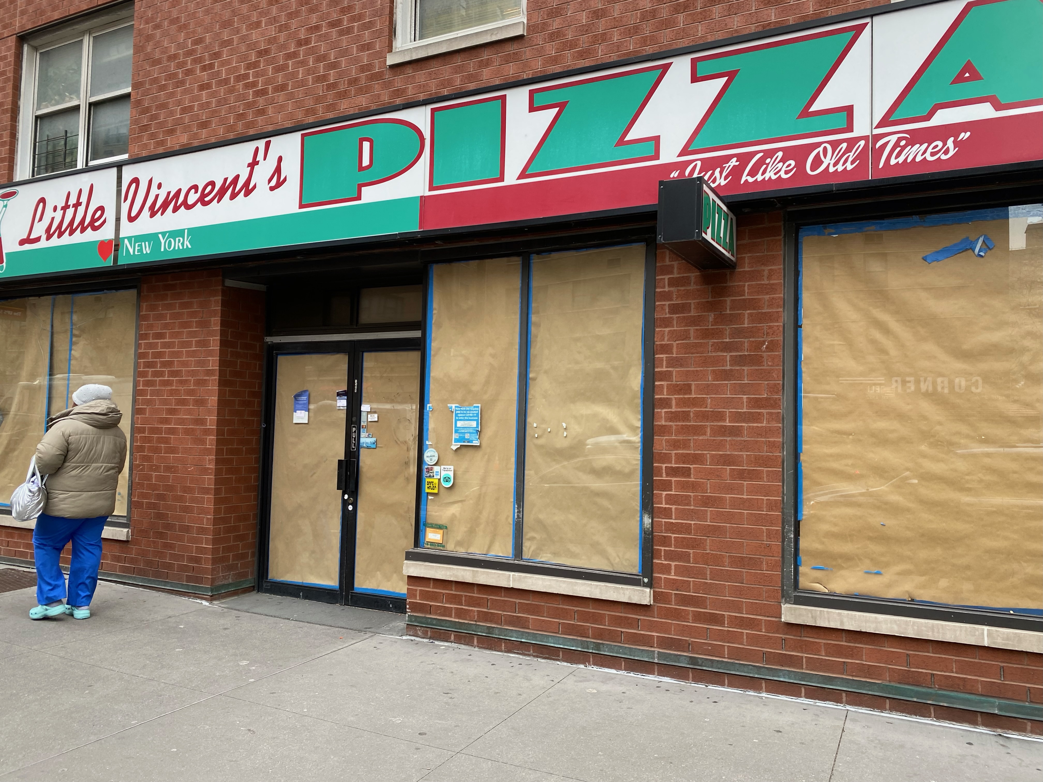 a woman walks past a little vincent 's pizza in new york