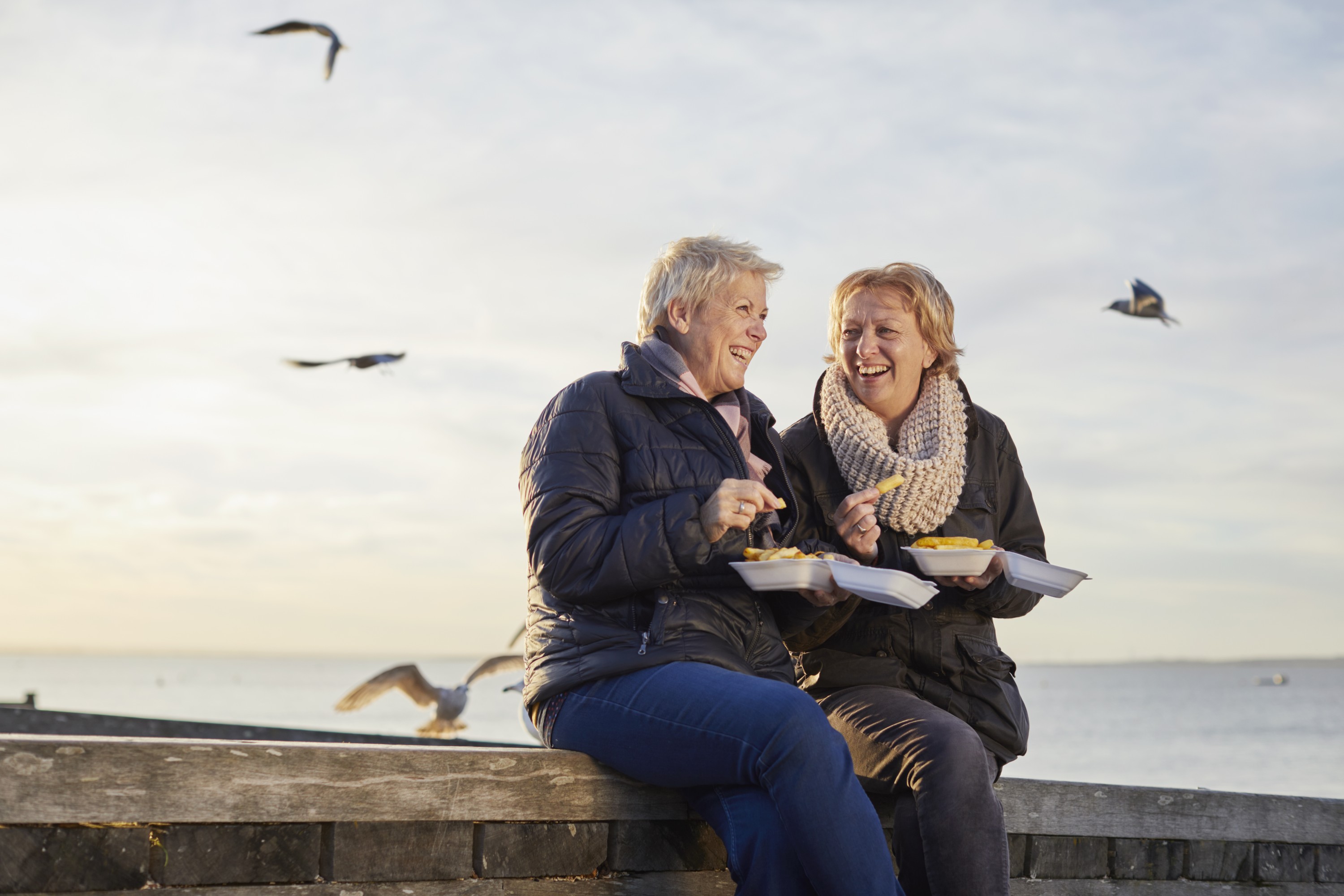 Two pensioners sitting on a wall by the seaside