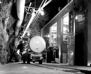 Black and white photograph of a truck driving in a tunnel underground.