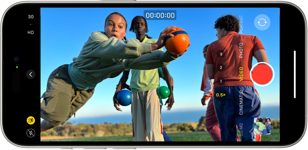 The iPhone is turned horizontally. Camera is open and in Video mode. In the camera frame, a person is jogging. The Flash button is in the bottom-left corner of the screen. The Camera Controls button is in the left-center of the screen. In the top-left corner are quick toggles to switch the video resolution and frame rate. The Action button in the top-left corner is turned on. At the right side are, from top to bottom, the Camera Chooser Back-Facing button, the Record button, and the Photo and Video Viewer button. Within the viewfinder, a person is running.