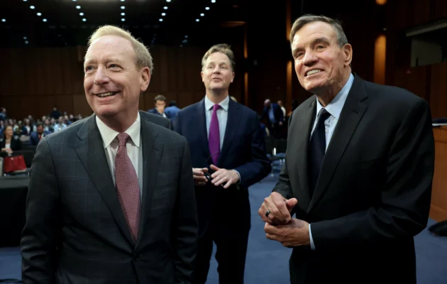 Brad Smith, Vice Chair and President of Microsoft, (L) and Nick Clegg (C), Chief of Global Affairs for Meta, talk with Co-Chair of the Senate Intelligence Committee U.S. Sen. Mark Warner (D-VA) before a Senate Select Committee on Intelligence heading in the Hart Senate Office Building on September 18, 2024 in Washington, DC. The committee heard testimony on foreign threats to U.S. elections in 2024, and how U.S. tech providers intend to respond to those threats. (Win McNamee/Getty Images)