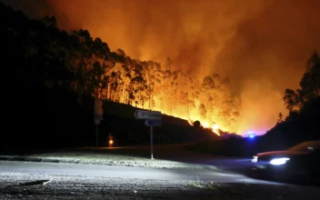 A car drives past a road closed by police as a wildfire burns close to it, near Sever do Vouga, a town in northern Portugal that has been surrounded by forest fires, on Sept. 16, 2024. (Bruno Fonseca/AP Photo)