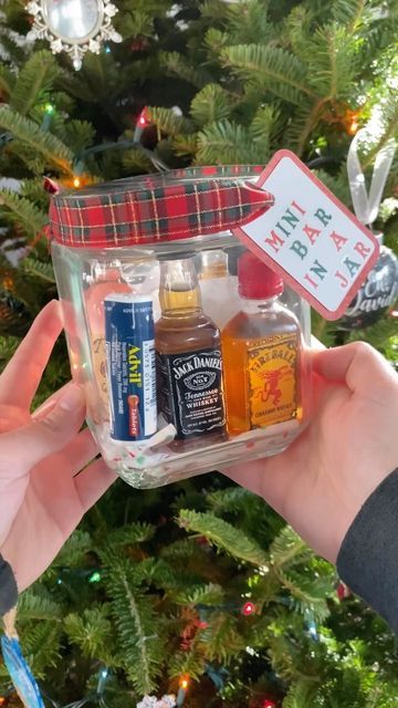 someone is holding up a jar with various things in it next to a christmas tree