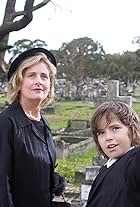 Miss Judy (Sonia Todd) and Joshua (Karl Beattie)  at the funeral. 